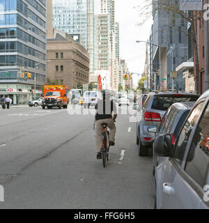 Un homme chevauche son vélo sur une rue de Manhattan. Banque D'Images