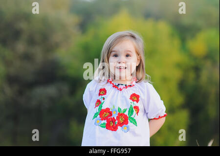 Petite fillette de 3 ans se réjouit émotionnellement. Une fille habillé en blanc costume national ukrainien avec des fleurs brodées. Banque D'Images