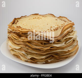 Pancakes ronds frits dans un grand tas sur une plaque sur un fond blanc Banque D'Images