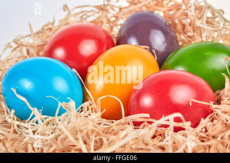 Six œufs de Pâques colorés dans la paille comme nid de Pâques. Banque D'Images
