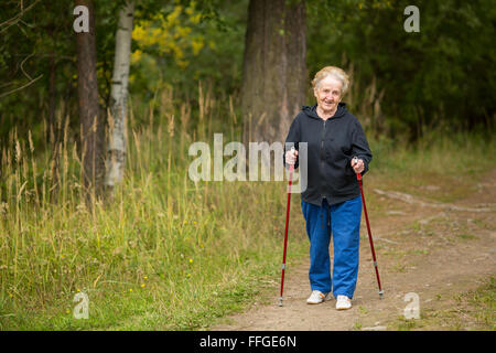 Femme âgée engagés dans la marche nordique dans le parc. Banque D'Images
