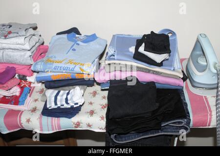 Planche à repasser avec fer à repasser et des vêtements pliés Banque D'Images