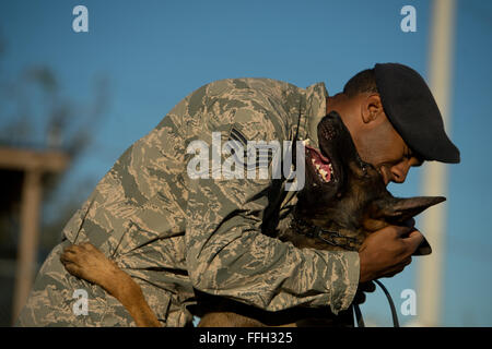 Le s.. Sharif DeLarge, un conducteur de chien de travail militaire du 802 e Escadron des Forces de sécurité, étreintes son chien de travail militaire OOlaf après une agression contrôlée à l'exercice Joint Base San Antonio-Lackland. DeLarge et chiens de travail militaire affecté à JBSA-Lackland remplissent les exigences de l'application de la loi tous les jours ou en train de rester prêt à la mission. Banque D'Images