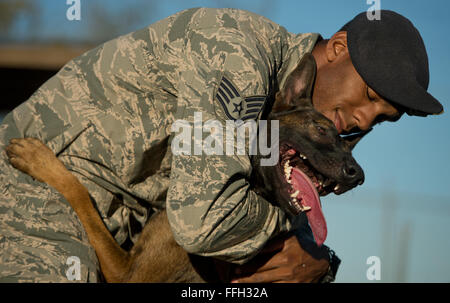 Le s.. Sharif DeLarge hugs son chien de travail militaire OOlaf après une agression contrôlée à l'exercice Joint Base San Antonio-Lackland, Texas. DeLarge et chiens de travail militaire affecté à JBSA-Lackland remplissent les exigences de l'application de la loi tous les jours ou en train de rester prêt à la mission. Banque D'Images