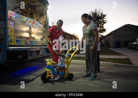 Somaya, 2, fille de sergent. Chantel Thibeaux, Base-Fort mixte Sam Houston, Texas, assistant dentaire instructeur, il atteint jusqu'à la crème glacée que sa grand-mère Carla guide sa grande roue. À deux ans, Somaya est pas au courant de son combat contre le cancer et les mères ont essayé de jouer avec elle toutes les chances qu'elle peut, mais est limité à certaines activités. Environ 15 parents et amis réunis chez elle pour célébrer le succès de la chirurgie et de fournir l'amour à Thibeaux au cours de sa quête pour vaincre le cancer. Banque D'Images