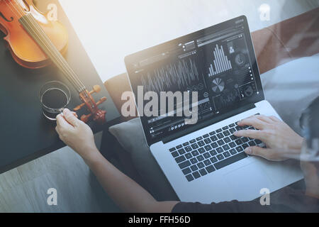 Hipster part composer de la musique avec ordinateur portable compter et sitting on sofa at home studio Banque D'Images