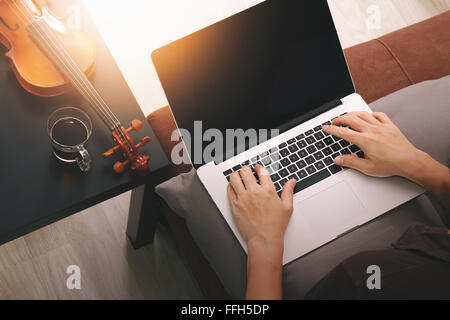 Hipster part composer de la musique avec ordinateur portable compter et sitting on sofa at home studio Banque D'Images