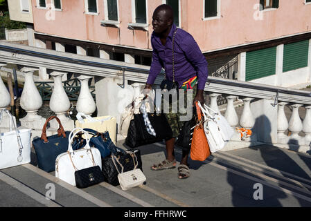 Un immigré africain, un vendeur de rue illégal, vendant des sacs à main pour femmes contrefaits tels que Gucci, Fendi et Prada aux touristes sur Ponte degli Scalzi (scal Banque D'Images