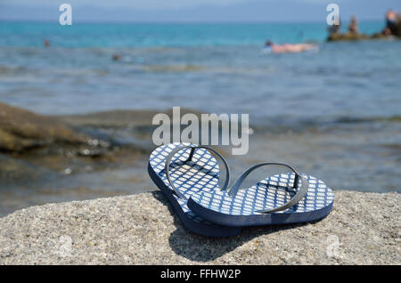 Les tongs bleu sur la plage par la mer Banque D'Images