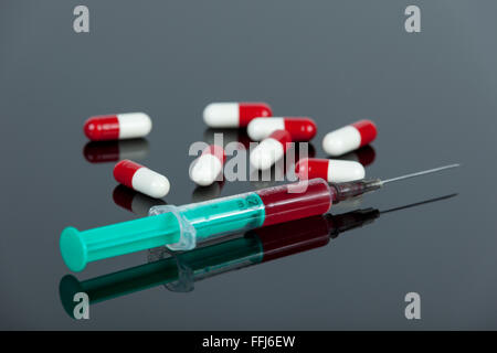 Aiguille hypodermique remplie de sang rouge et blanc, avec des capsules de médicaments portant sur reflective lab 24 Banque D'Images