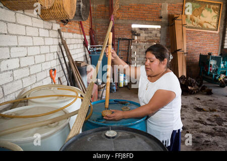 Matatlán Santiago, Oaxaca, Mexique - en une distillerie de Mezcal, une femme tire un échantillon pour les visiteurs de goûter. Banque D'Images