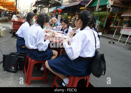 Les élèves du secondaire thaïlandais bénéficiant d''un bol de soupe thaï aux vermicelles dans un petit restaurant de rue à Bangkok. Banque D'Images