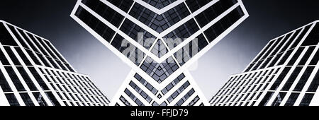 Verre moderne immeuble de bureaux de grande hauteur avec des angles aigus montrant les réflexions d'un ciel clair bleu vif en monochrome. Tonique bla Banque D'Images