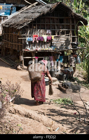 Tribal Muun woman sweeping son homefront en milieu rural l'État de Chin, Myanmar Banque D'Images