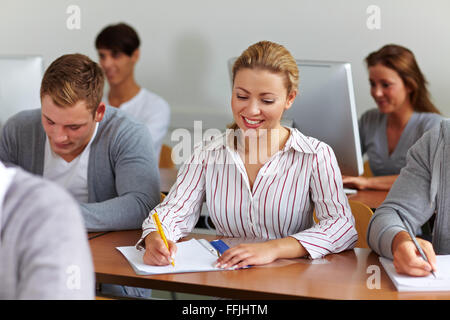 Happy female student taking notes in classe universitaire Banque D'Images