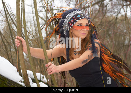 Girl in native american coiffure sur l'arbre dans la forêt d'hiver Banque D'Images