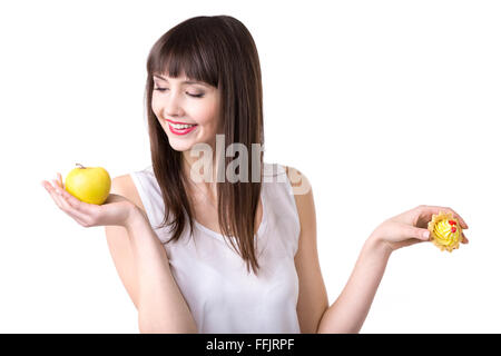 Young happy woman holding apple frais et délicieux gâteau tarte à la crème, en choisissant des fruits plutôt que des desserts sucrés, sain Banque D'Images