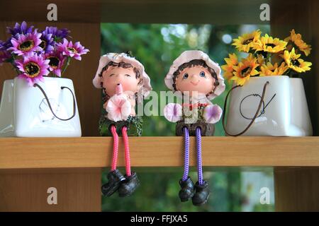 Cute les poupées en céramique avec rose, violet et jaune fleurs dans des sacs Banque D'Images