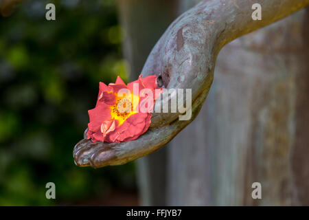 Fleur jaune et rouge dans la main d'une statue Banque D'Images