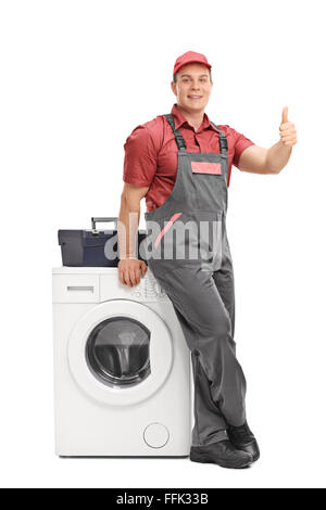 Portrait d'un réparateur d'hommes s'appuyant sur une machine à laver et donner un pouce vers le haut isolé sur fond blanc Banque D'Images
