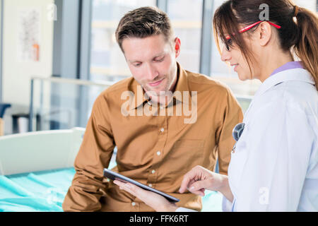 Femme médecin et patient looking at digital tablet Banque D'Images