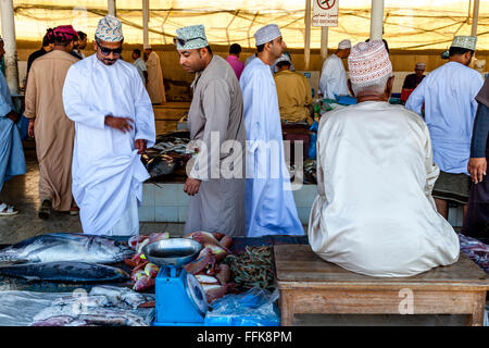 Les hommes en costume traditionnel omanais d'acheter du poisson au marché aux poissons, Muttrah, Muscat, Sultanat d'Oman Banque D'Images