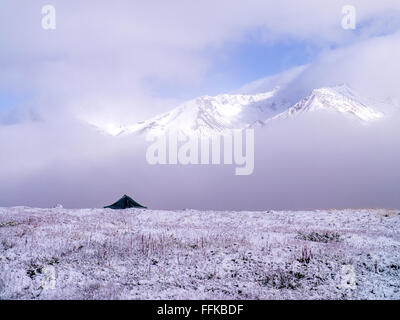 Une tente solitaire pendant sur une crête en face d'une montagne couverte de neige en hiver ; Wrangell St Elias National Park, Alaska Banque D'Images