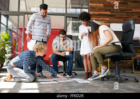 Les gens créatifs à projet au plan établi sur le sol. Mixed Race associés discutent de nouvelles plan de projet modern Banque D'Images