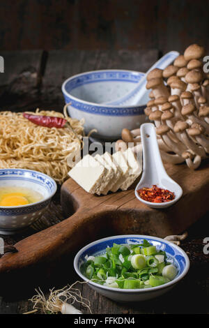 Ingrédients pour soupe ramen asiatique. Nouilles, petits oignons, fromage feta, champignons, oeuf et de piment dans des bols asiatique porcelan ov Banque D'Images