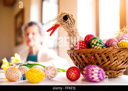 Panier avec des œufs de Pâques et poule dans senior woman house Banque D'Images