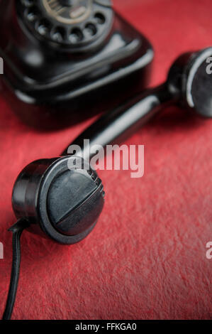 Vieux téléphone avec le combiné décroché sur fond rouge Banque D'Images