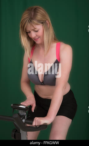 Portrait d'une jolie femme blonde l'ordinateur avant de monter un vélo d'exercice pour maintenir sa forme physique Banque D'Images