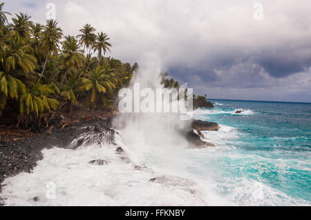Broyage des grosses vagues sur le rivage d'une île tropicale avec des palmiers au cours d'une tempête. Praia Piscina - Sao Tomè et Principe. Banque D'Images