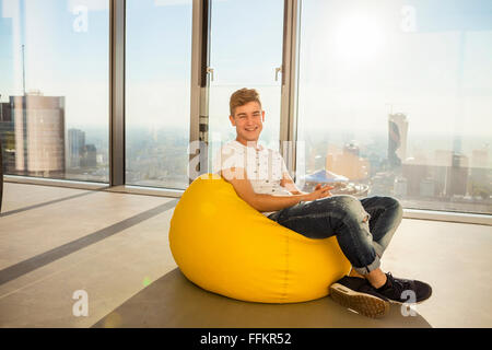 Stagiaire masculin détente dans un bureau moderne contre paysage urbain Banque D'Images