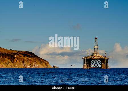 Le dirigeant d'une plate-forme pétrolière flotte dans l'Estuaire de Cromarty, dans le nord de l'Ecosse comme une mouette vole juste au-dessus de l'horizon. Banque D'Images