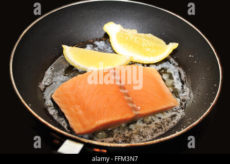 Saumon cru avec du beurre et du citron dans une poêle Banque D'Images