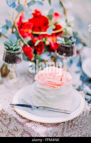 Gâteau de mariage blanc orné de fleurs sur fond de bois Banque D'Images