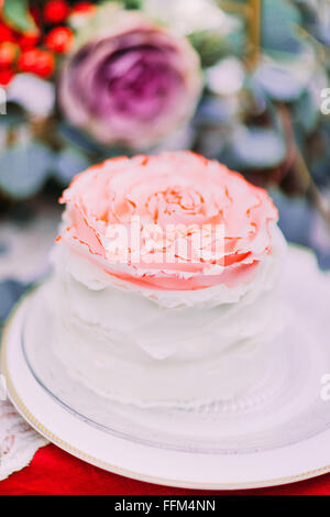 Gâteau de mariage blanc orné de fleurs sur fond de bois Banque D'Images