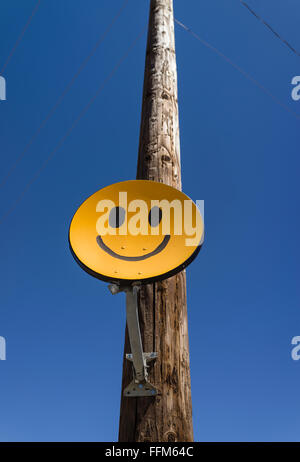 Un smiley orange jaunâtre antenne satellite reliée à un poteau téléphonique en bois dans la vallée centrale de Californie. Banque D'Images