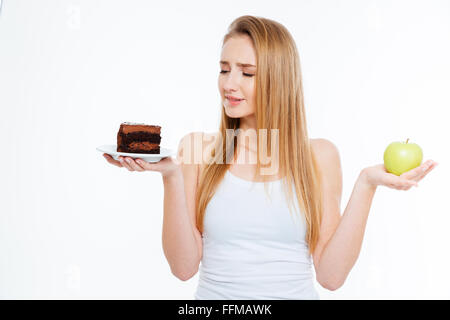 Jeune femme confuse entre le choix d'aliments sains et malsains sur fond blanc Banque D'Images