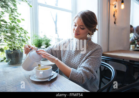 Happy woman drinking tea in cafe Banque D'Images