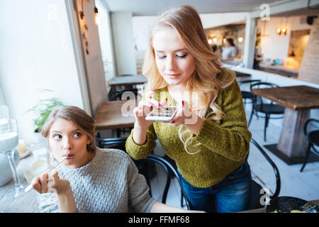 Young woman photographing food on smartphone in restaurant Banque D'Images