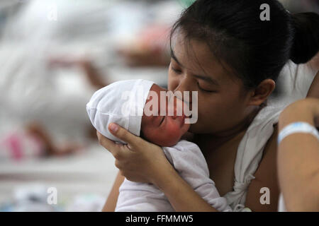 Manille, Philippines. 16 Février, 2016. Une mère embrasse son enfant nouveau-né à l'intérieur de la maternité de l'Hôpital Memorial Dr. Jose Fabella à Manille, Philippines, 16 février 2016. Le ministère philippin de la Santé a informé les femmes à ne pas tomber enceinte jusqu'à cette année on en sait davantage sur la transmission de Zika virus qui cause des anomalies des naissances en Amérique latine, en dépit du fait que les Philippines' seul cas signalé de Zika était il y a quatre ans. Credit : Rouelle Umali/Xinhua/Alamy Live News Banque D'Images