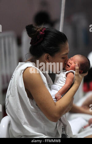 Manille, Philippines. 16 Février, 2016. Une mère embrasse son enfant nouveau-né à l'intérieur de la maternité de l'Hôpital Memorial Dr. Jose Fabella à Manille, Philippines, 16 février 2016. Le ministère philippin de la Santé a informé les femmes à ne pas tomber enceinte jusqu'à cette année on en sait davantage sur la transmission de Zika virus qui cause des anomalies des naissances en Amérique latine, en dépit du fait que les Philippines' seul cas signalé de Zika était il y a quatre ans. Credit : Rouelle Umali/Xinhua/Alamy Live News Banque D'Images