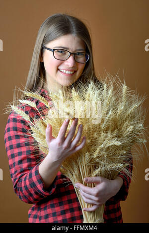 Tenir en main fille bouquet de tiges de blé tourner en studio Banque D'Images