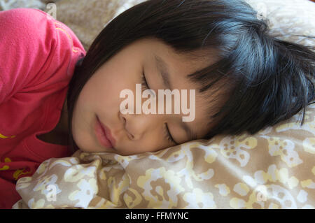 Petite fille dormir sur lit chaud Banque D'Images