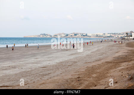 Les hommes omanais jouant au football sur la plage à Muscat Banque D'Images