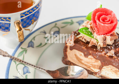 Gâteau au chocolat à la main sur une soucoupe avec cuillère et une tasse de thé Banque D'Images