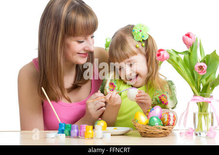 Mère et enfant fille heureuse à la préparation de pâques et oeufs à colorier avec brosse Banque D'Images