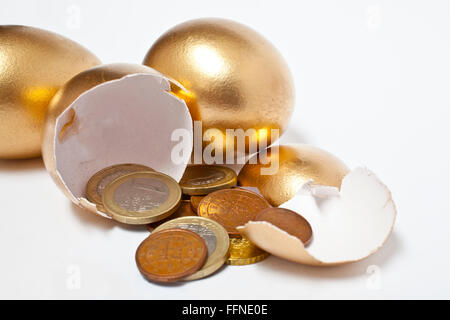 Les oeufs d'or avec les pièces en euros Banque D'Images